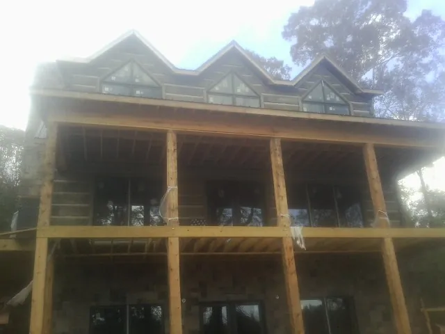 Dormers and porch framing on a large log home under construction — Roof Coating work by our crew in Hague