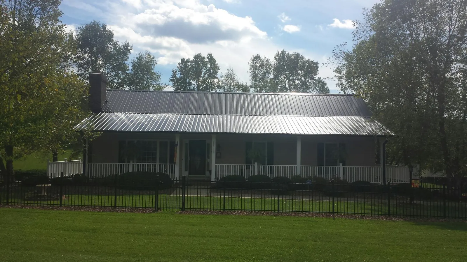Gray metal roof on a brick ranch with a full width front porch — Gutter Guard Installation work by our crew in Hague